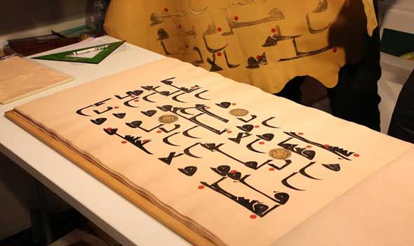 خطاط إيراني ينسخ سورة الرحمن على قطع الجلد في معرض الشارقة
