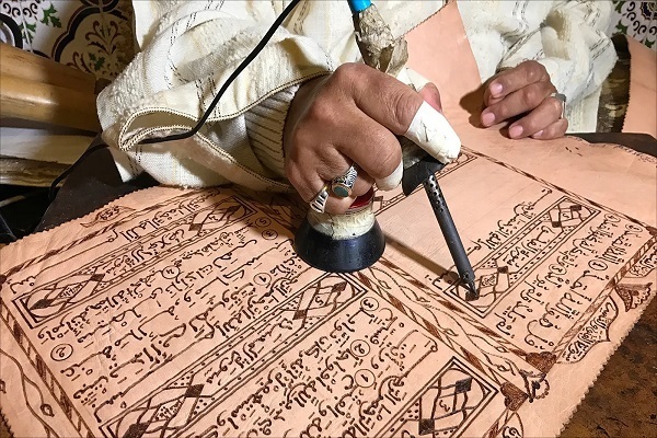 Künstlerische Kreativität des behinderten marokkanischen Künstlers beim Schreiben des Korans auf Ziegenhaut