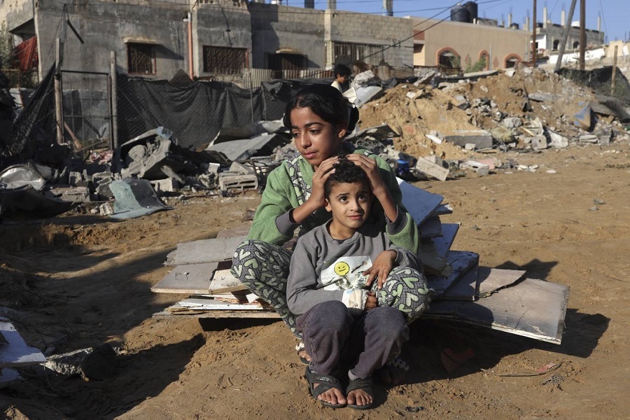 A Palestinian girl and her brother sit amidst the debris of a house following an Israeli strike in Rafah in the southern Gaza Strip on November 18, 2023. (Photo by AFP)