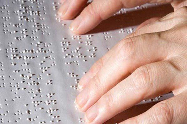 A visually-impaired person reading a book in braille