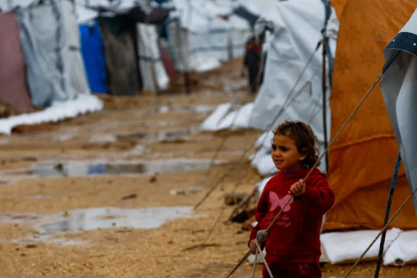 A displaced Palestinian child in a tent camp on a rainy day in Nuseirat, the central Gaza Strip.