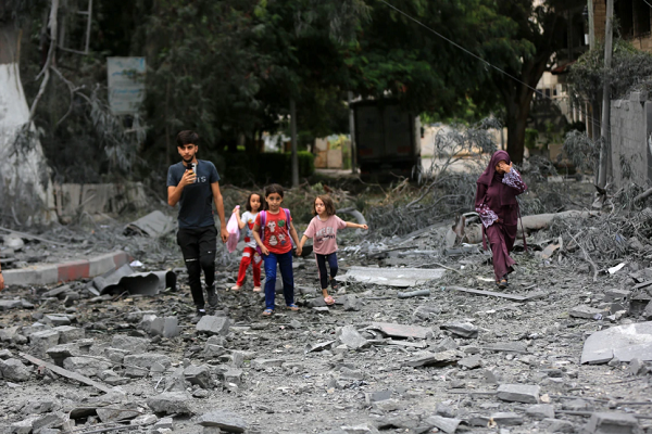 People in Gaza moving through the rubble of a building destroyed in Israeli bombings