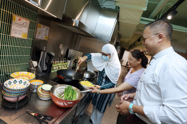 Pakistani resident Azmat Tariq (left) uses HUB13’s halal kitchen as Bill Lay, Caritas Hong Kong’s senior social work supervisor (right), looks on.