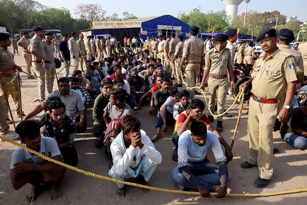 Police officers stand next to men they believe to be undocumented Bangladeshi nationals after they were detained during raids in Ahmedabad, India on April 26, 2025.