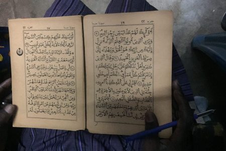 همنشینی تاجر سنگالی با قرآن در ازدحام بازار + عکس