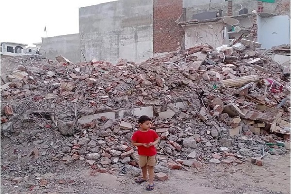 کودک سرگردان در کنار تلی از آوار خانه تخریب شده