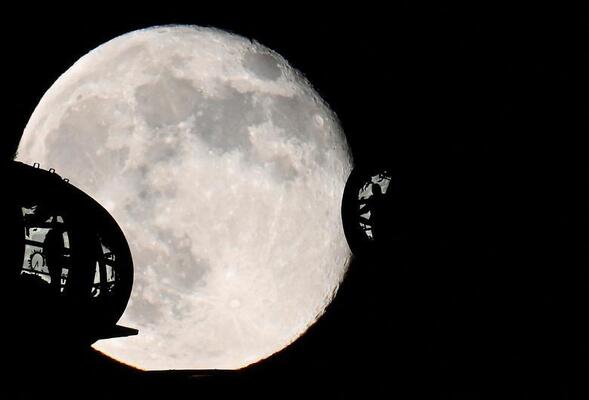 مسافران از روی غلاف های چرخ چشم لندن به ماه نگاه می کنند، بریتانیا.