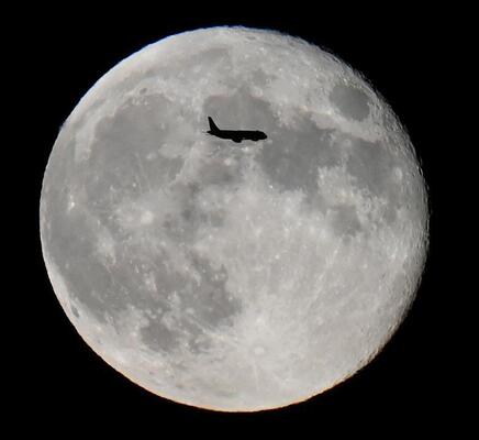حرکت یک هواپیما از مقابل ماه بر فراز لندن، بریتانیا 