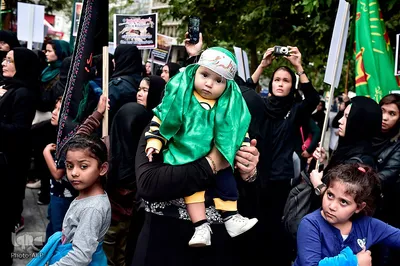 یک زن دارای یک لباس مذهبی؛ مسلمانان شیعه در میدان سنتاگما در آتن نماز ظهر عاشورا را اقامه می کنند