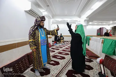 حنا حمادی 18 ساله، 7 سال است که در تعزیه خوانی ایفای نقش می کند. ابتدا با معرفی دوستان بازیگرش به تعزیه خوانی روی آورد؛ حنا همچنین بازیگر تئاتر است و در این تعزیه نقش حضرت زینب (س) را اجرا می کند. 
همچنین فرزاد رضایی پور، 27 سال دارد. 7 سال است که تعزیه خوانی را اجرا می کند او علاوه بر این، بازیگر تئاتر کودکان هم هست. در این تعزیه نقش عمر بن سعد را ایفا می‌کند.
در این تصویر آقای رضایی‌پور و خانم حمادی هر دو در حال تمرین پیش از اجرا هستند.