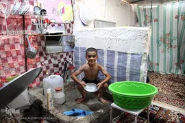 استحمام یکی از کودکان خانواده های مستاجر زلزله زده در محله زعفران سرپل ذهاب که بلاتکلیف در کانکس زندگی می کنند