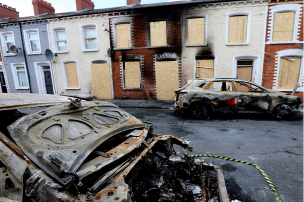 Burned cars and boarded-up houses after racist riots on the streets of Belfast in early June 2026.