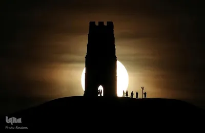 طلوع ماه کامل در پشت برج سنت مایکل در  در Glastonbury انگلیس 