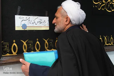 تبرک جستن حجت‌الاسلام قربان‌پور با پرچم گنبد امام رضا(ع)