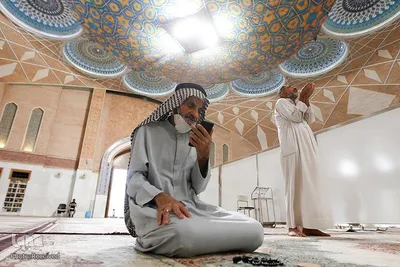 مردی عراقی با استفاده از تلفن همراه خود در مسجدی در شهر نجف، ادعیه می خواند. 
