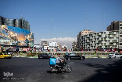 میدان ولیعصر مردموتور سواری که در حال گذر است. پیک‌های موتوری به علت ارتباط با افراد مختلف از مشاغل آسیب پذیرند.