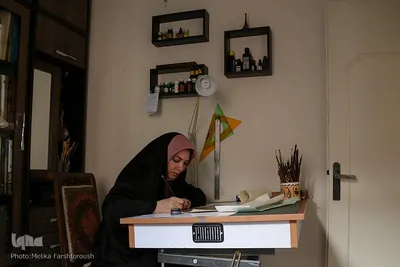 مهرناز قربان‌پور در اتاق کار در حال خطاطی
